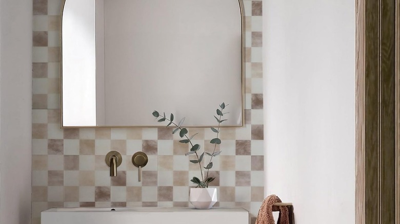Checkerboard beige and off-white peel and stick tiles installed on a bathroom sink wall