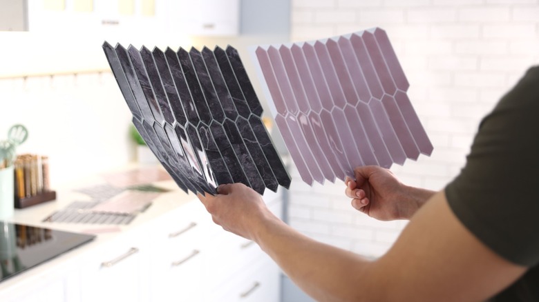 Person comparing two colors of peel-and-stick tile for kitchen backsplash