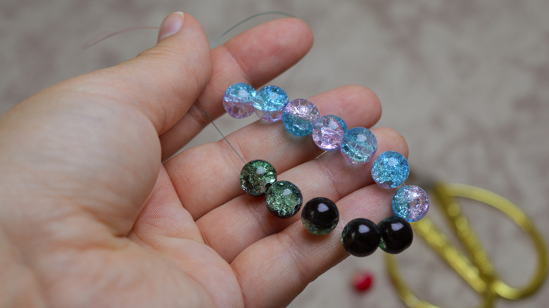 A hand holding a string with colorful beads on it