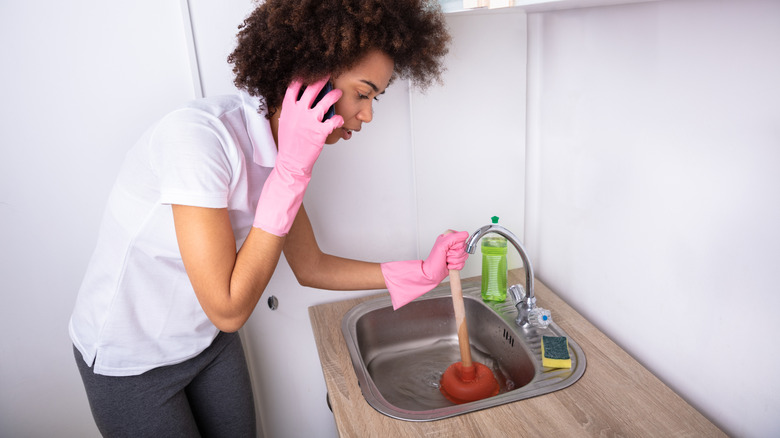 Woman plunging the sink and calling for help