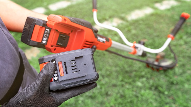 Worker installing a battery in a cordless string trimmer