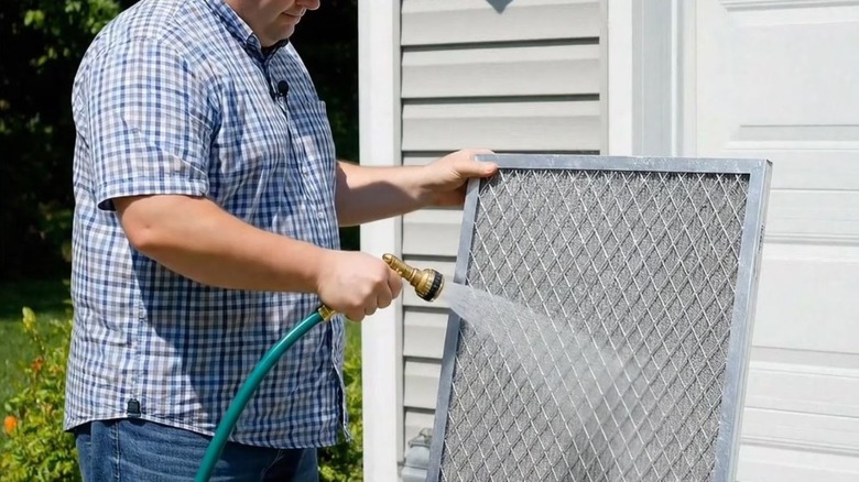 Man rinsing a washable air filter with a hose