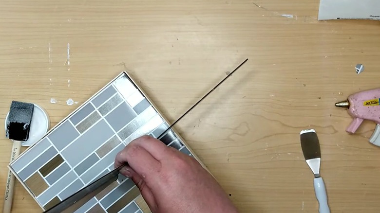 Woman DIYing a geometric subway tile style stand for DIY toilet paper rod