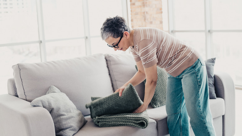 Woman folding up a blanket in a spacious living room