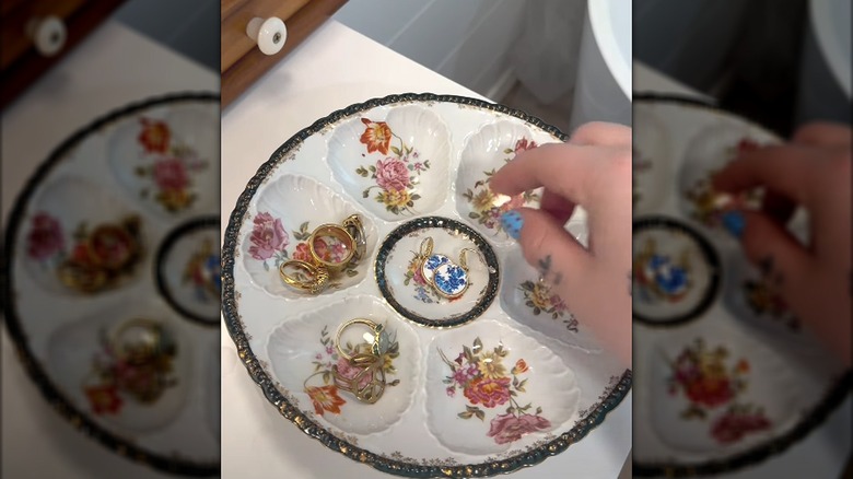 Person reaching for jewelry stored in an oyster plate