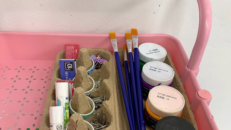 Pink rolling cart with an egg carton in it holding craft and office supplies