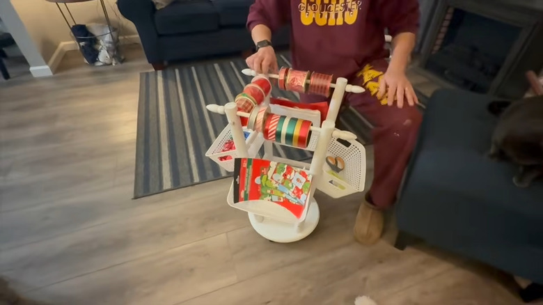 Person organizing wrapping paper supplies in an organizer made from an old wooden stool