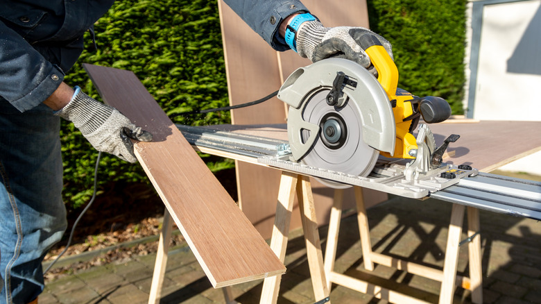 A person sawing boards with a circular saw