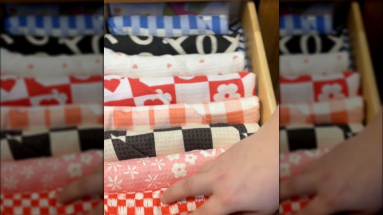 Person lining up folded towels in a drawer
