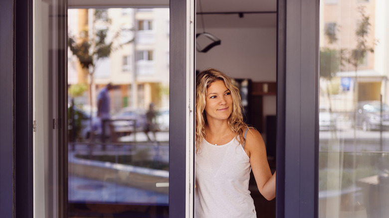 A person looking out of an open sliding glass door