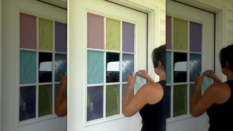Person covering window panes with tissue paper