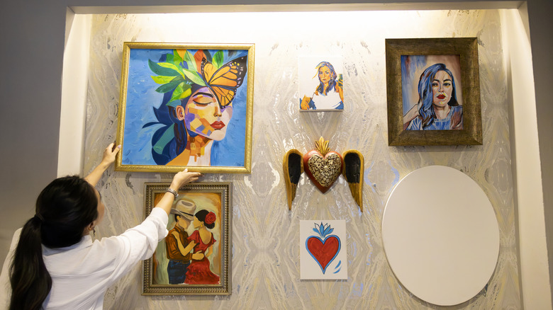 Woman hanging gallery wall with a variety of art work