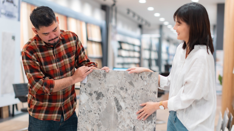 A man and woman holding a gray stone countertop slab
