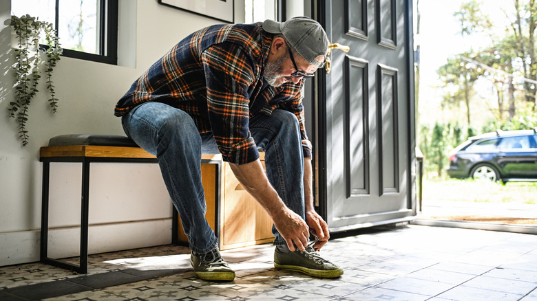 Man putting on shoes in entryway of home