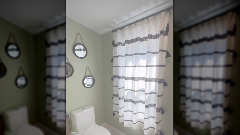 A striped shower curtain hanging on a curtain rod next to a toilet