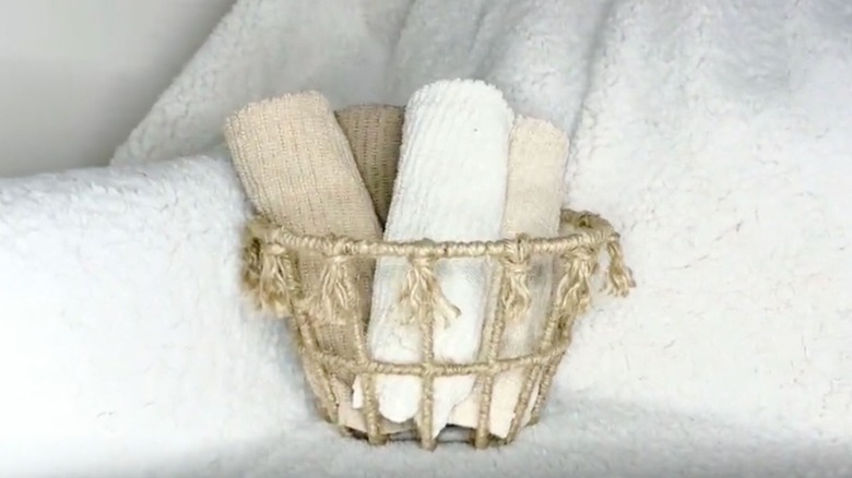 A jute-wrapped wire basket holds an assortment of neutral colored kitchen towels