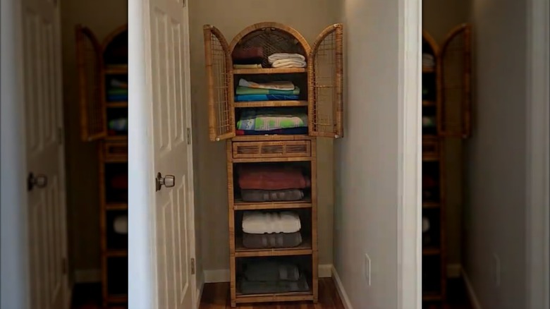 Wicker freestanding hutch at the end of a hallway used to hold towels