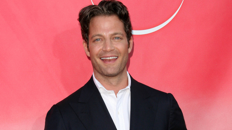 Nate Berkus smiling at the camera against a red background