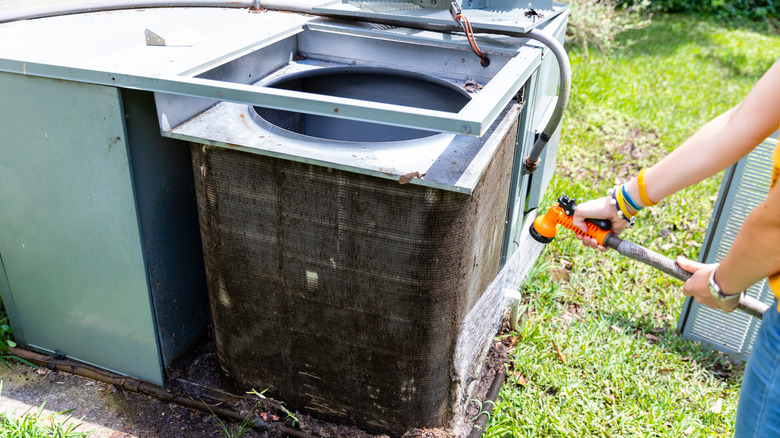 Person cleaning an outdoor AC unit