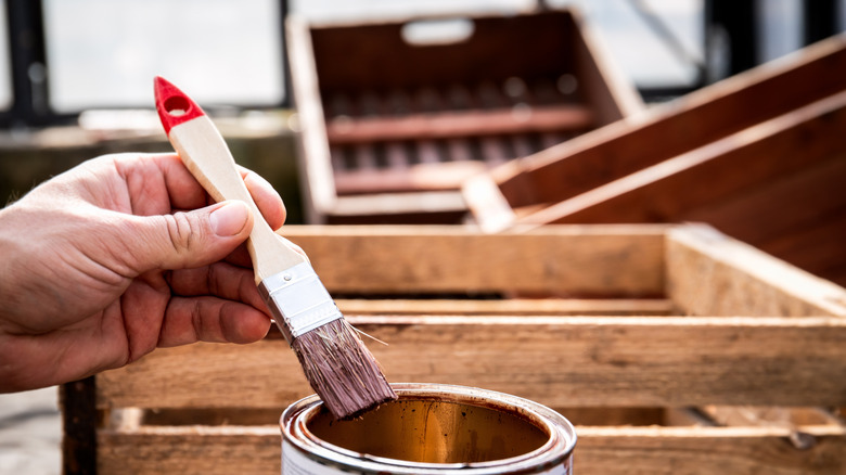 Person holding a paint brush with wood pallets in background