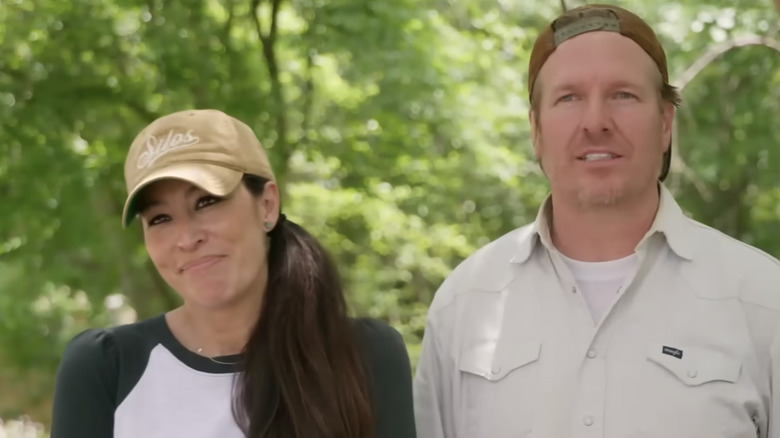 A closeup of Joanna Gaines and Chip Gaines with trees in the background.