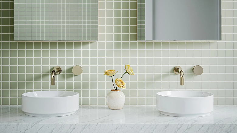 A double bathroom vanity with a backsplash of small square tiles in a sage green color with white grout lines