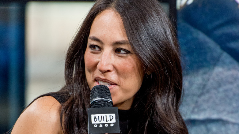 Joanna Gaines is talking into a microphone away from the camera