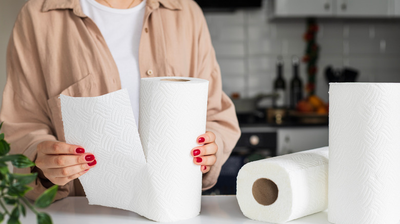 Woman tearing sheet from paper towel in kitchen