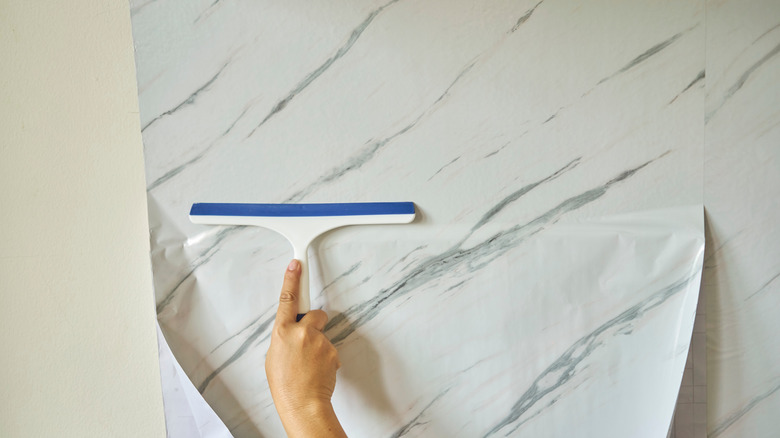 Person applying peel and stick wallpaper to their wall