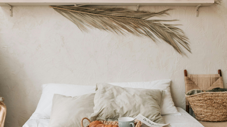 A dried palm leaf hangs on the wall above a bed
