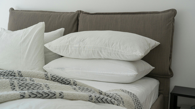 Two mushroom pillows sit upright against a wall on a crisp white bed
