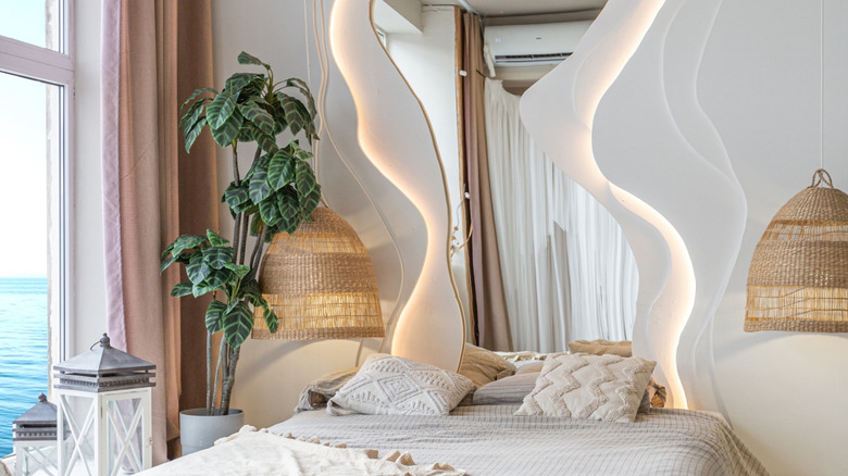 An organic-shaped mirror framed by LED lights is installed in a coastal bedroom