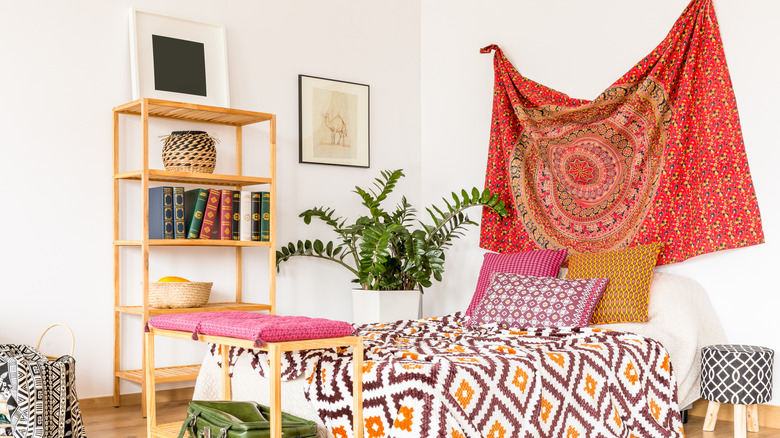 A bright red tapestry hangs in a bohemian bedroom