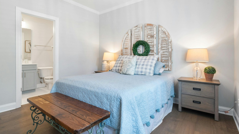 Weathered shutters hang on the wall behind a bed