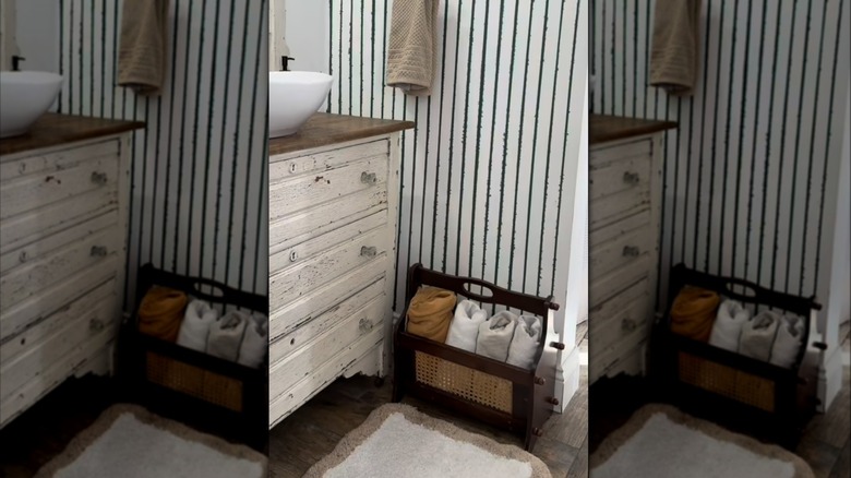 Wood magazine rack holding rolled towels in a bathroom