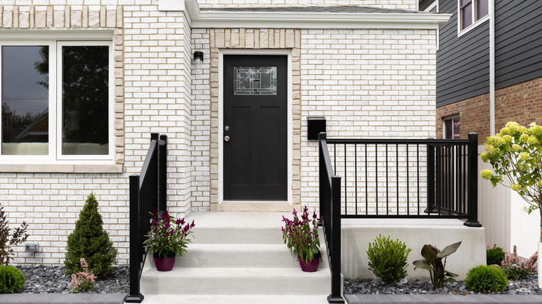 white brick house with a black front door and concrete porch