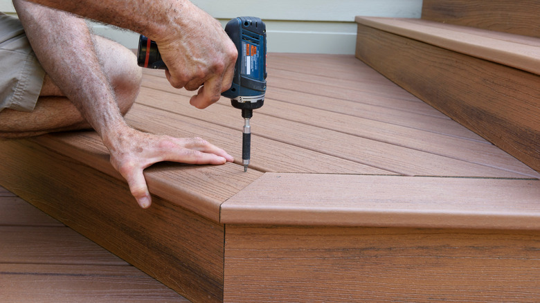 person installing wood-look composite decking on exterior stairs