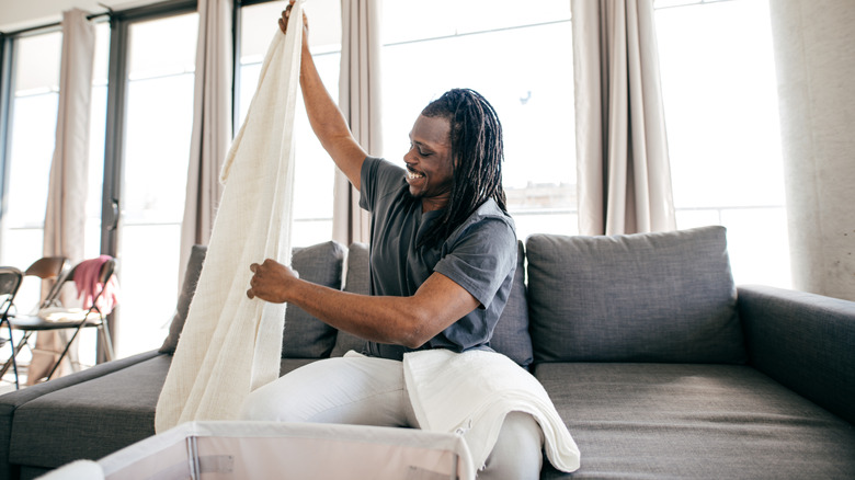 Man folding linens in the living room