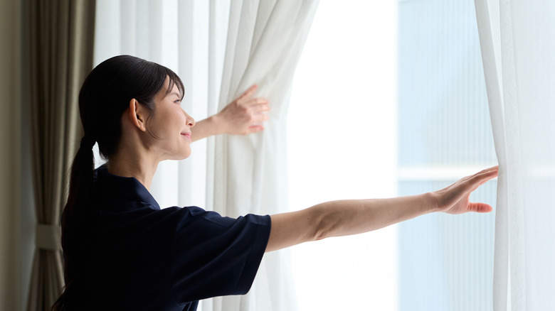 Woman opening the curtains