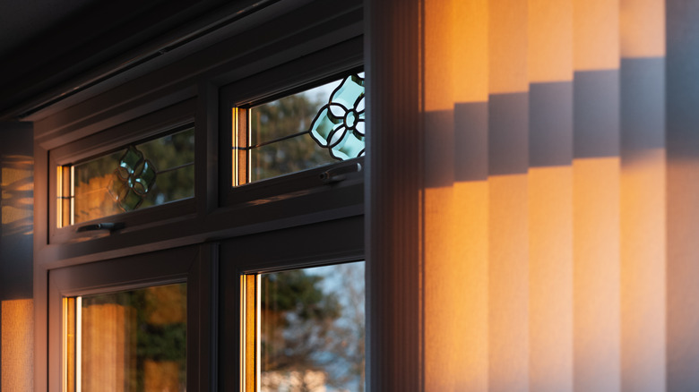 vertical blinds in glowing evening sunlight over stained glass window