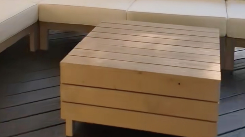 Square wooden coffee table in the middle of an outdoor seating arrangment