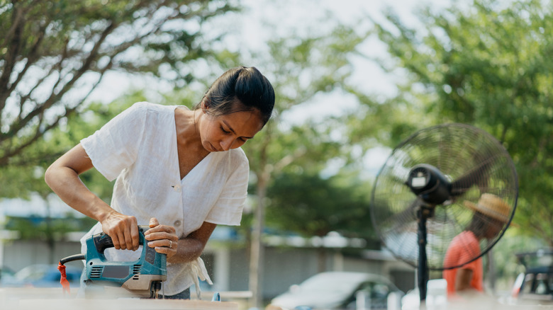 Woman cutting wood in her driveway for a DIY project