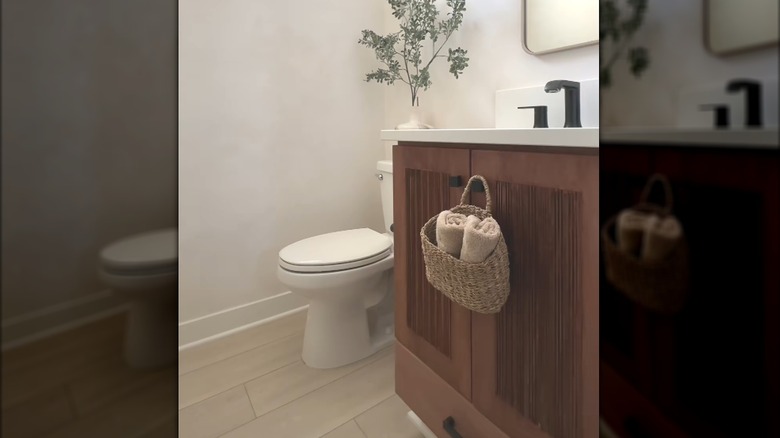 Hanging woven basket hanging on warm wood cabinet countertop in classic modern bathroom