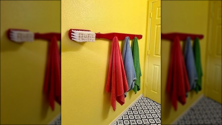 Red towel rack shaped like toothbrush with colorful towels