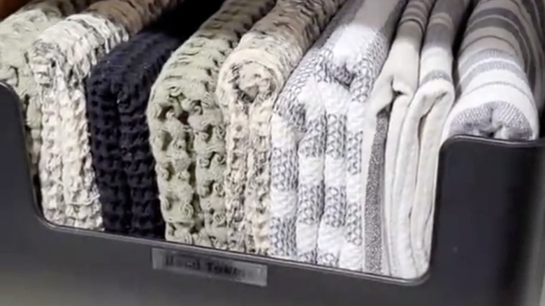 Towels folded and stored vertically in a plastic organizer bin
