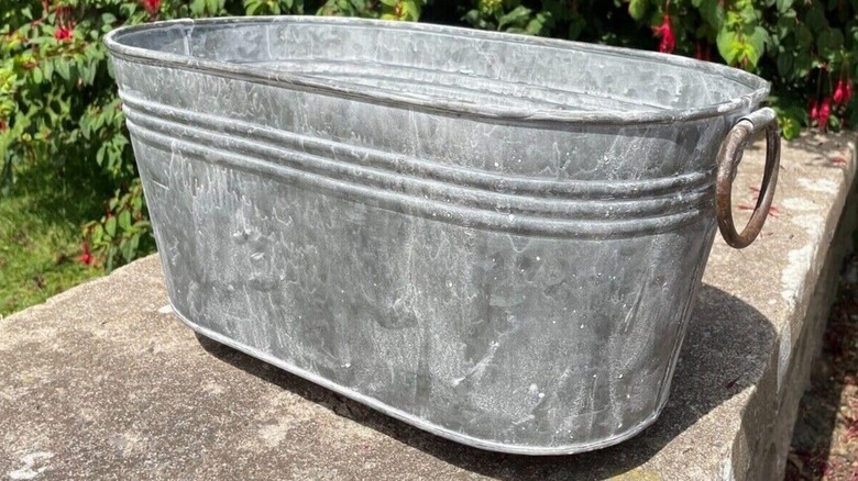 Man setting up DIY galvanized tub ottoman with hidden storage in living room on wood floor