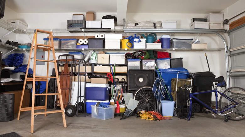 View of messy garage shelving with clutter on floor