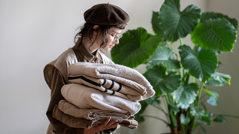 A woman carries a stack of blankets
