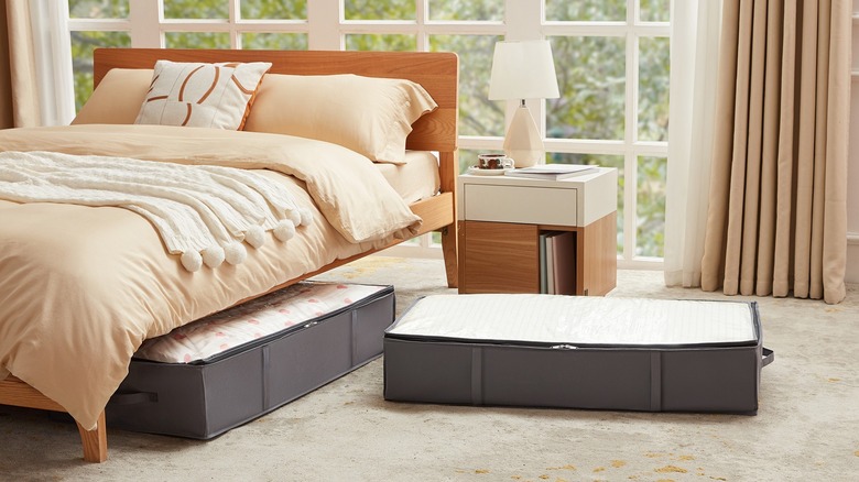 Two gray under-bed storage boxes with blankets on the floor