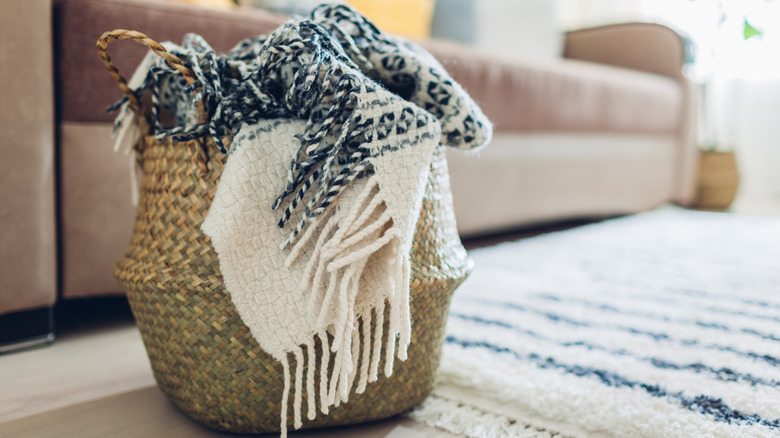black and white blanket in wicker basket placed in a living room
